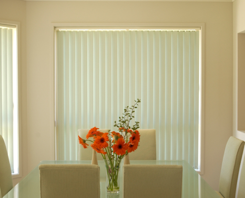 Vertical blinds with an orange flower in the dining table