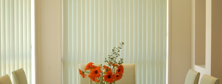 Vertical blinds with an orange flower in the dining table