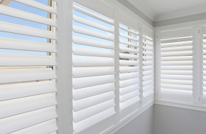 Closeup shot of white shutters allowing visibility of the outdoors