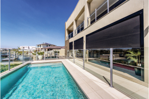 Black straight drop awnings covering the windows of an apartment with pool